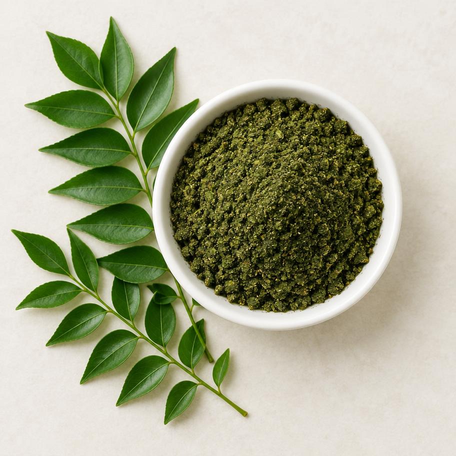Green curry leaf podi powder in a bowl with fresh curry leaves