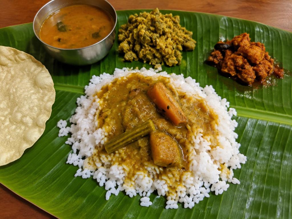 Banana leaf meal with rice, sambar, curry and chicken pickle on the side